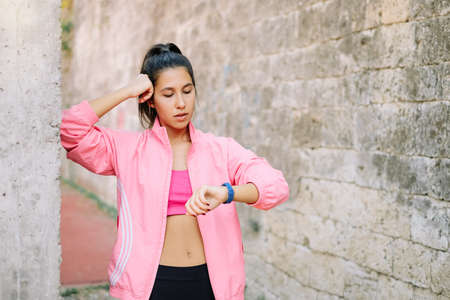 Tired girl checking her fitness tracker after workout