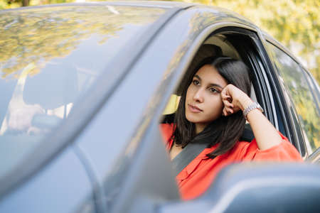 Elegant woman in red top driving a car