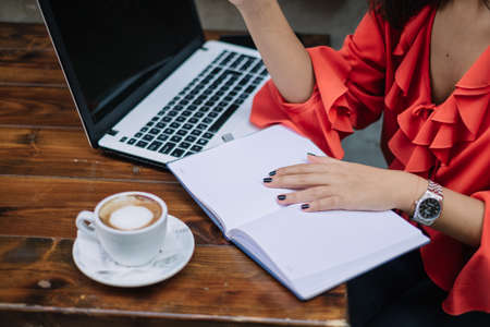 Notebook with woman's hands on wooden table