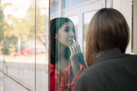 Reflection of a woman applying makeup outdoorsの写真素材