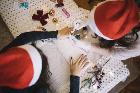 Manicurist with Santa hat doing Christmas manicure