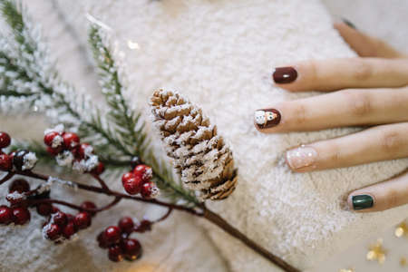 Girls hands with Holiday manicure and pine branchの写真素材