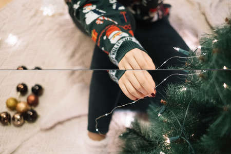 Girls hands adding Christmas lights to a treeの写真素材