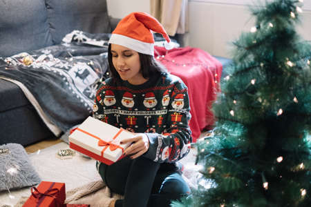 Woman sitting on floor with wrapped Christmas giftの写真素材