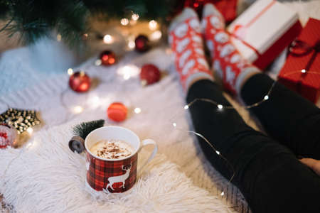 Female legs under Christmas tree with deer mugの写真素材