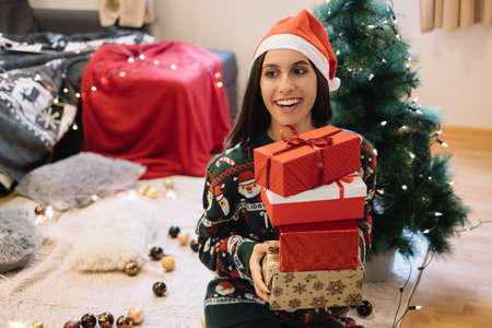 Happy girl holding wrapped gifts in front of Christmas treeの写真素材