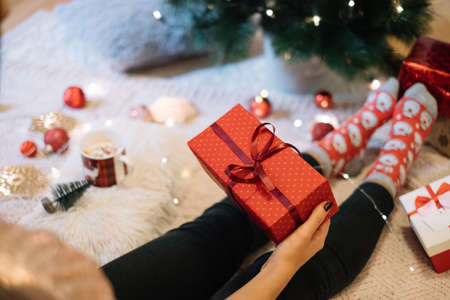 Female hand holding Christmas gift next to treeの写真素材
