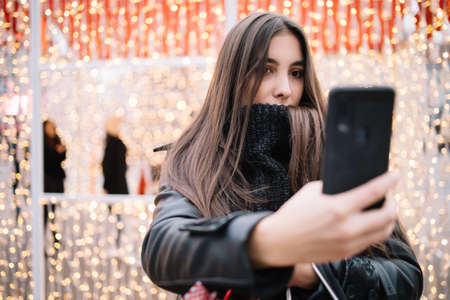 Brunette woman wearing neck sweater making selfieの写真素材