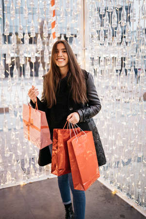 Brunette girl smiling while holding gift bags
