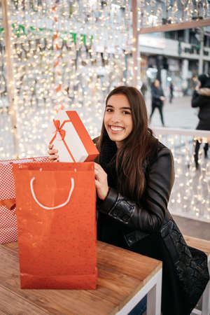 Girl sitting outside cafe with gift bags and presentの写真素材