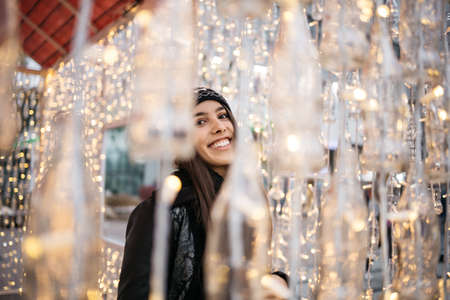 Happy woman standing behind blurred lights garlandsの写真素材