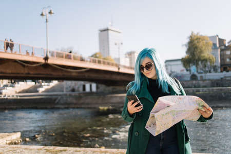 Travel woman looking at phone while standing side river. Attractive woman looking at her phone and...