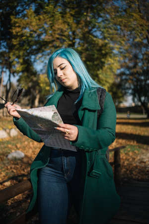 Lost solo tourist girl looking a map in park