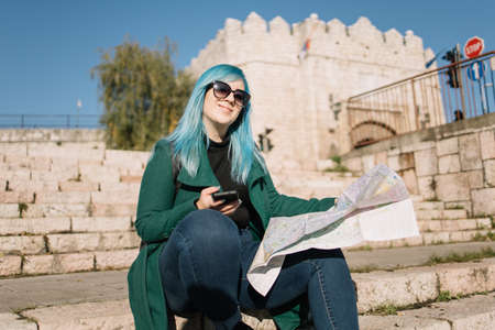 Tourist woman looking at her phone while sitting on stairs