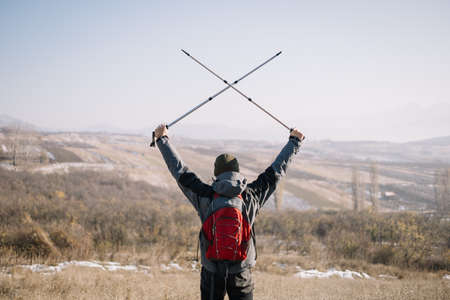 Back of man holding crossed poles in the air