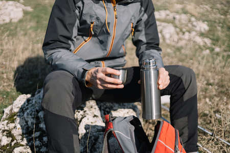 Close-up of males hands holding opened thermos