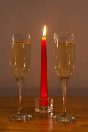 Wine glasses and burning candle on romantic light. Valentines day romantic decoration with wine glasses and burning red candle on wooden table.の写真素材