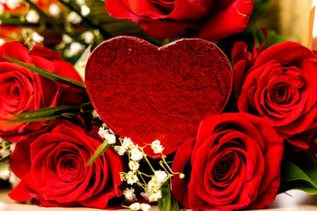 Red roses and gypsophila with heart shaped chocolate. Close-up of a bouquet of red roses and...
