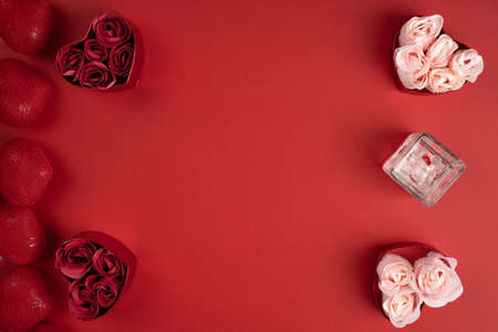 Perfumed candle and hearts with roses for Valentine's day. Scented candle and paper roses in heart shaped boxes on red background, flat lay.の写真素材