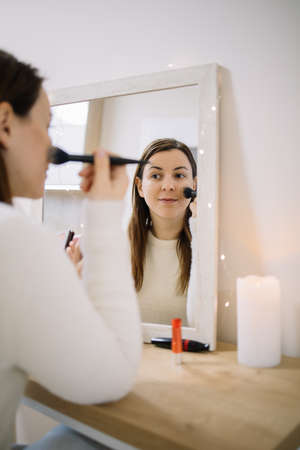 Mirrored image of a woman blushing her cheeks
