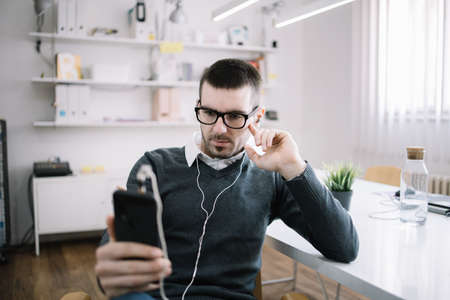 Office guy using phone and listening music in office