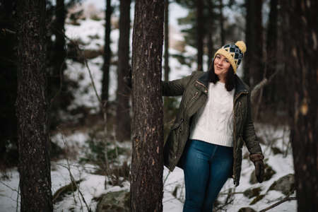 Smiling woman holding tree in the forestの写真素材