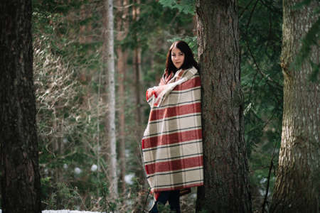 Pretty girl leaning on a tree in winter
