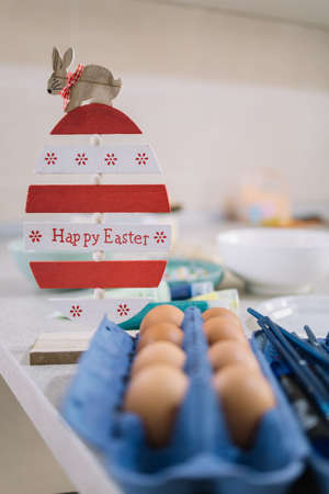 Easter decoration with not pained eggs in box. Big egg decoration with bunny on top next to a blue...