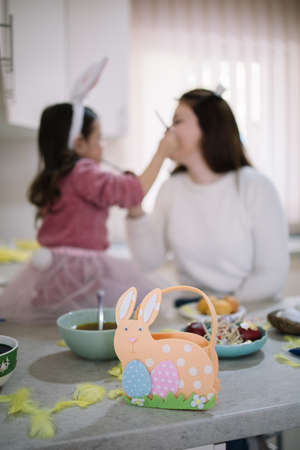 Felt basket for Easter on kitchen countertop. Decorated for Easter basket with blurred mother and...