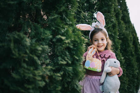 Little girl in rabbit ears holding felt basket and bunnyの写真素材