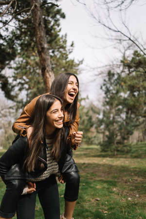 Two twin sisters having fun in the parkの写真素材