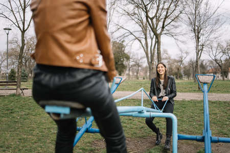 Beautiful women on rocking chair laughing in parkの写真素材