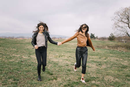 Girls running towards camera and holding handsの写真素材