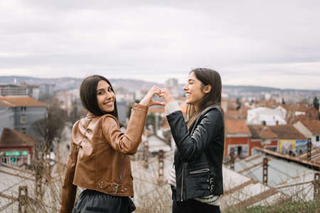 Brunette girls making a heart shape with their hands
