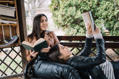 Girls resting in pavilion and holding books