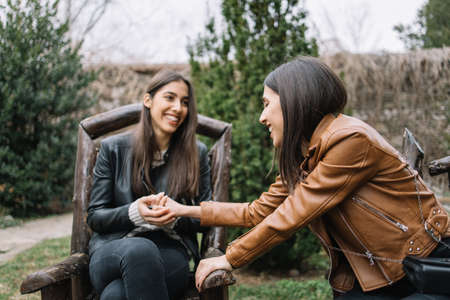 Girl holding her sisters hands while sitting in wooden chairの写真素材