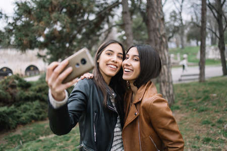 Sisters smiling against phone and making selfieの写真素材