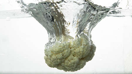 Cauliflower causing water splash with white background. Cauliflower with water splashes and white...