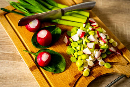Scallions sliced on wooden surface with knifeの写真素材