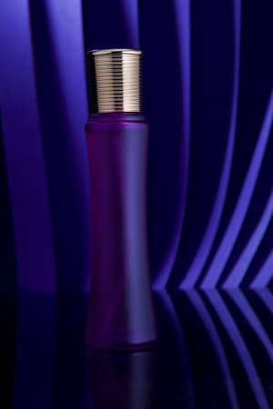 Purple perfume bottle with golden cap on blue backgroundの写真素材