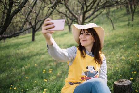 Girl with hat taking selfie in garden