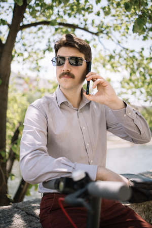 Man with sunglasses and moustache speaking on the phone