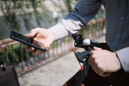 Man using phone while holding electric scooter rudder