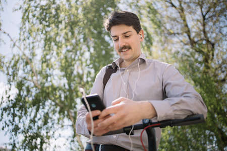 Close-up view of guy with earphones using smartphone outdoorの写真素材