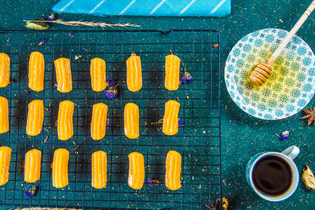 Pastry on grid near cup with coffee and honey. Top view of syrupy dessert tulumba arranged on grid...