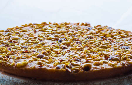 Close-up view of baked cake with chopped hazelnuts. Dessert with chopped nuts against white...
