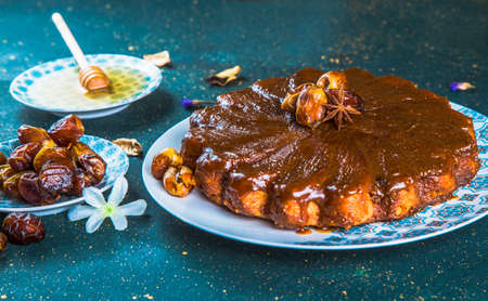 Cake with glaze and dates on table with honey. Close-up view of glazed dessert with ganache and...