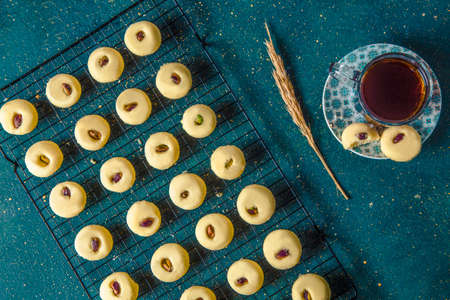 Sweet butter cookies with nuts on grid. Fresh baked nut biscuits on grid next to cup of tea, flat...