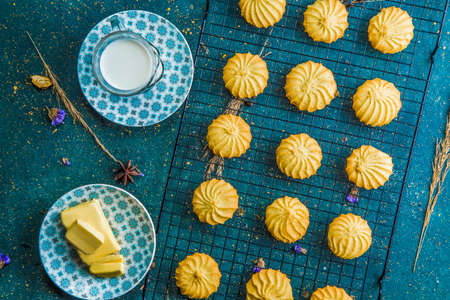 Fresh baked biscuits on grid with butter and milk. High angle view of biscuits on grid on blue table...