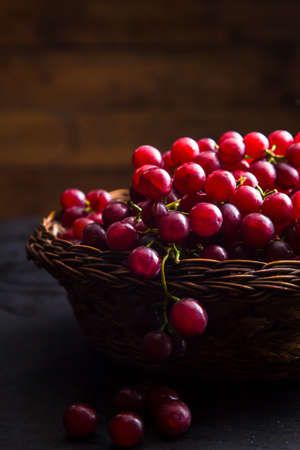 Close-up view of juicy grapes in wicker bowl. Healthy grapes in wicker basket on table with wooden background.の写真素材
